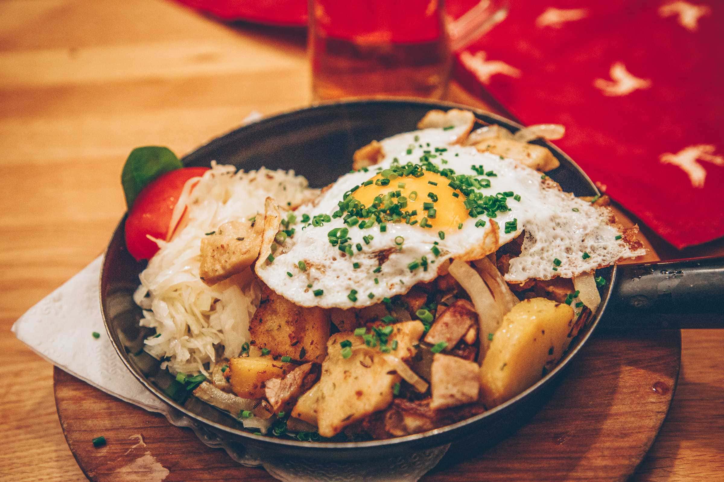 Gröstl with fried potatoes and fried egg in pan