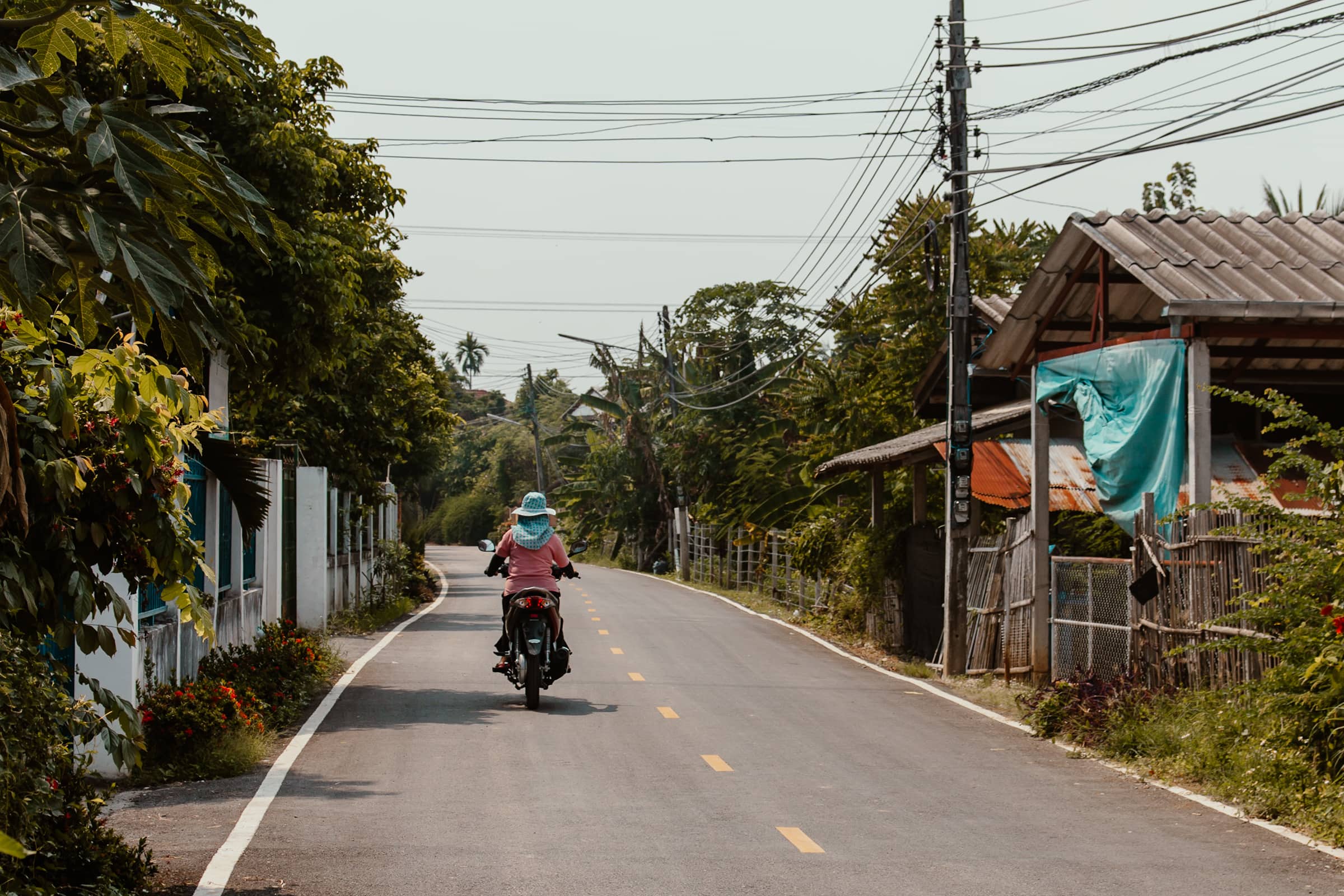 Estrada rural à volta de Chiang Mai, Tailândia, com um ciclista