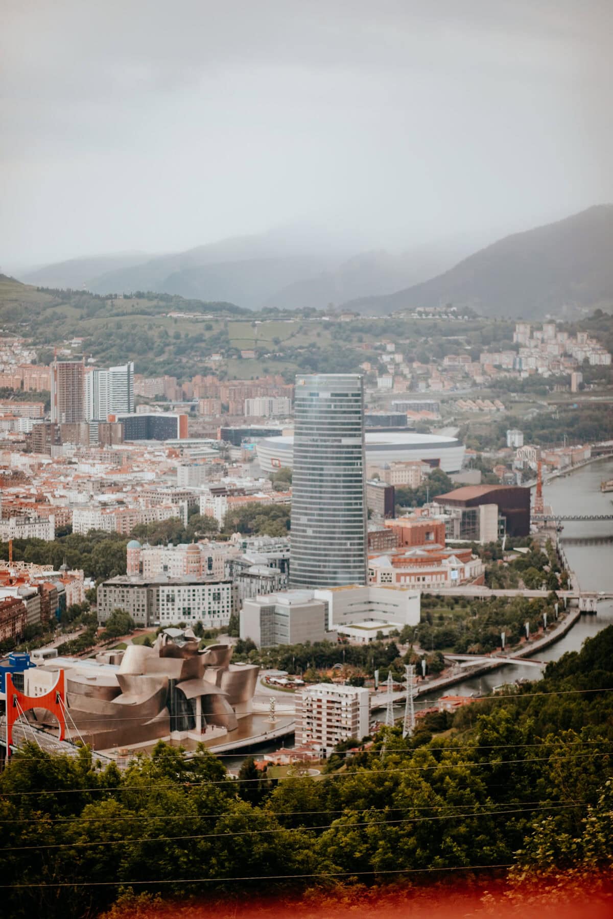 Cityscape with modern architecture and green hills.