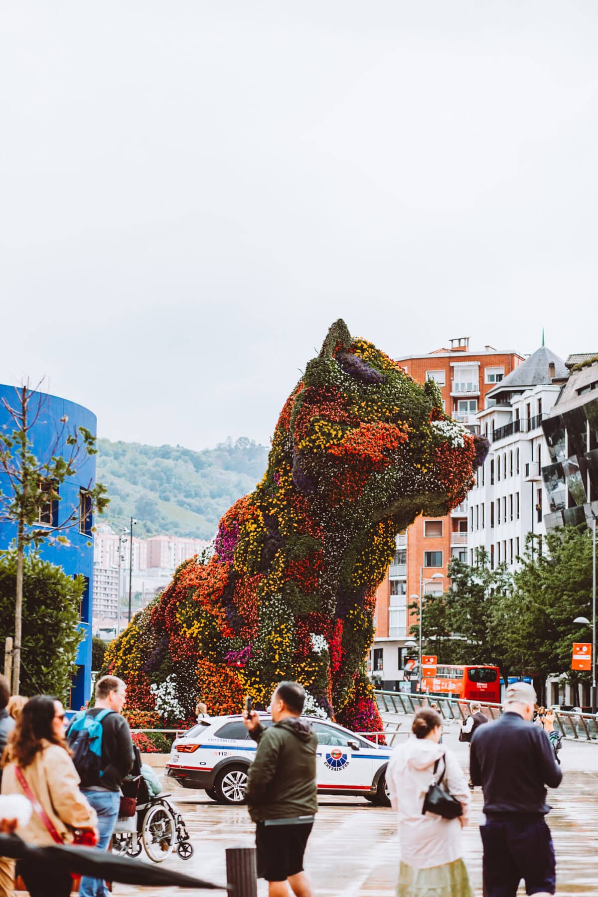 Flower dog sculpture in urban landscape.