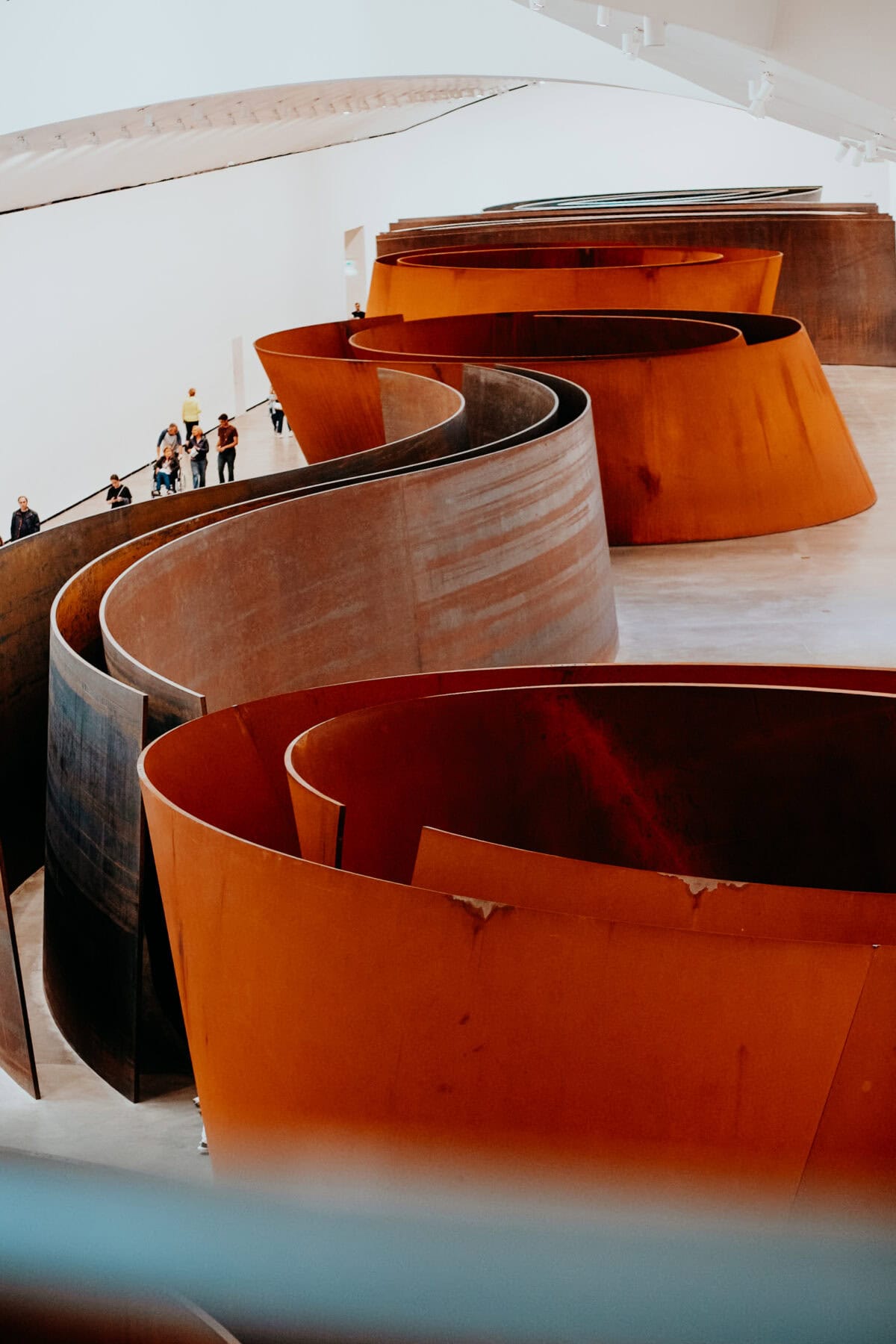 Modern metal sculpture in a gallery with visitors.
