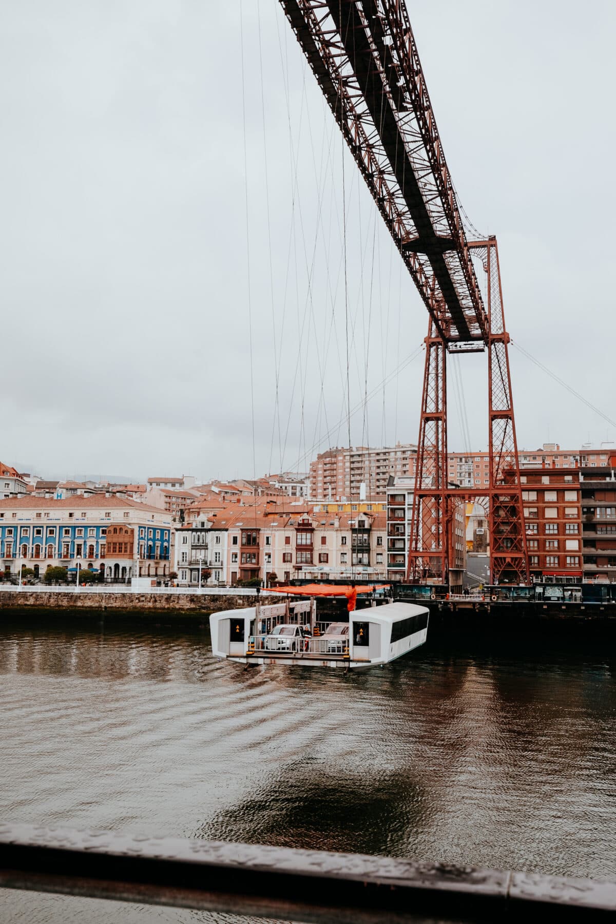 Bridge over river with ferry and colorful houses.