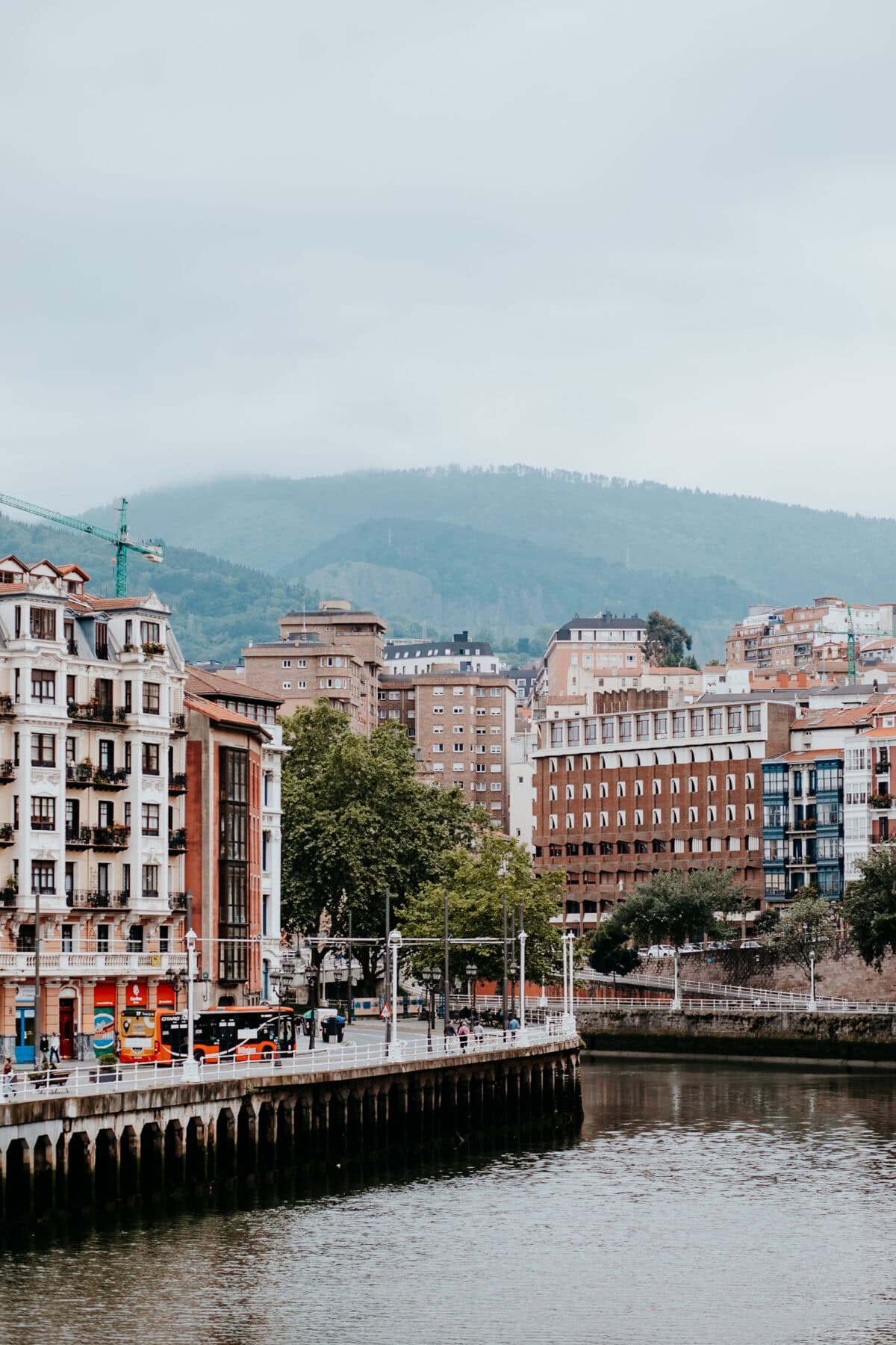 City view with river and wooded hills in the background.