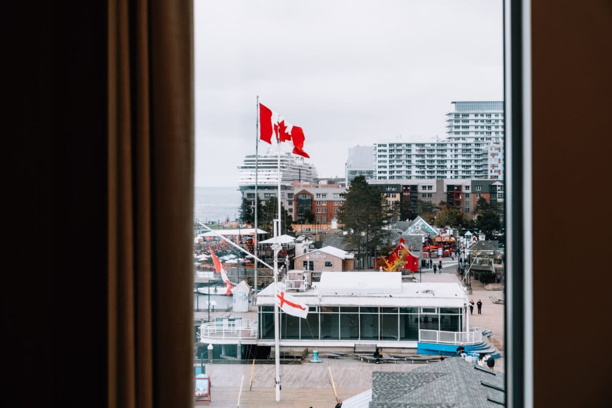 Canadian flag flies over harbor view in city.
