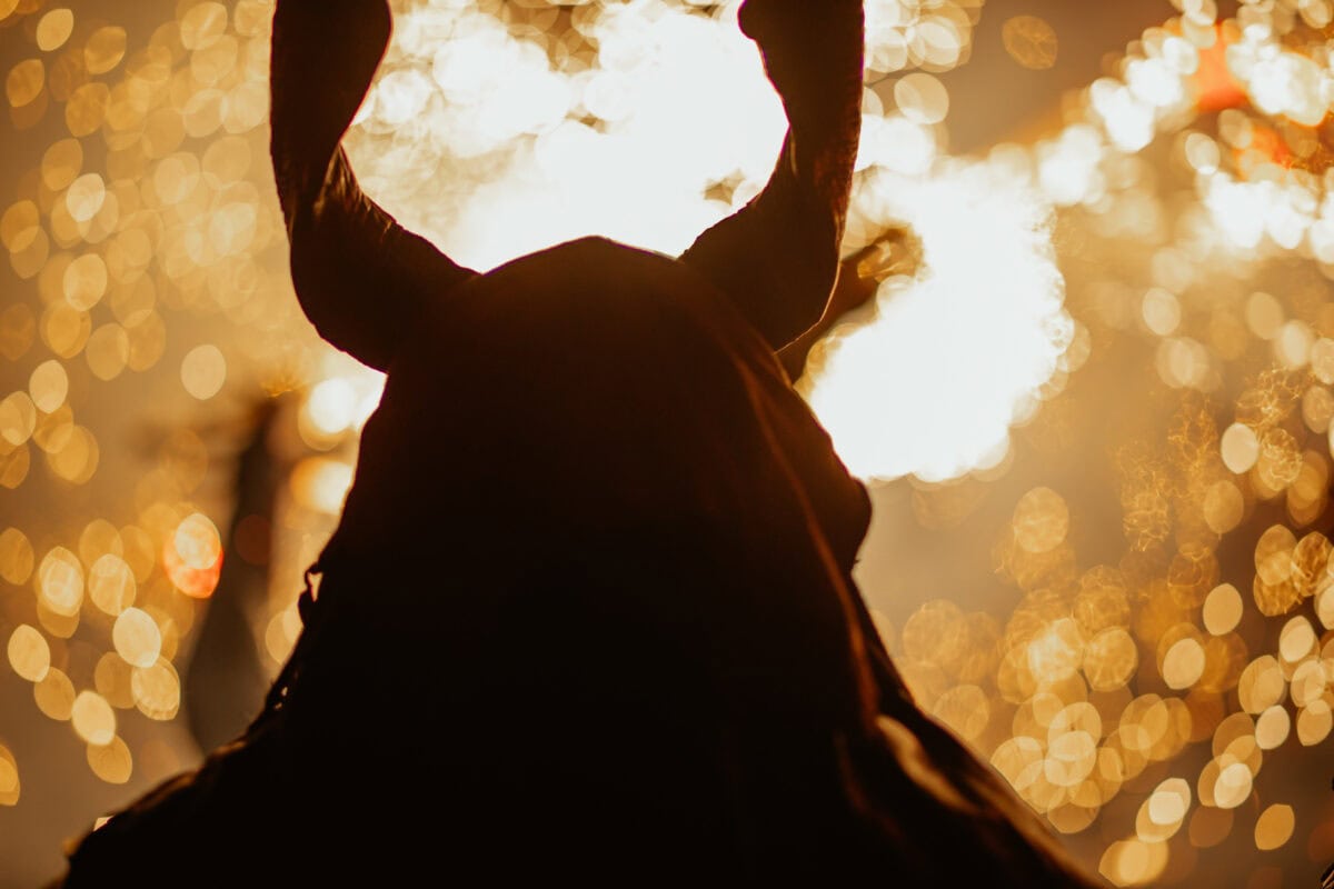 Silhouette with horns in front of sparks and light.