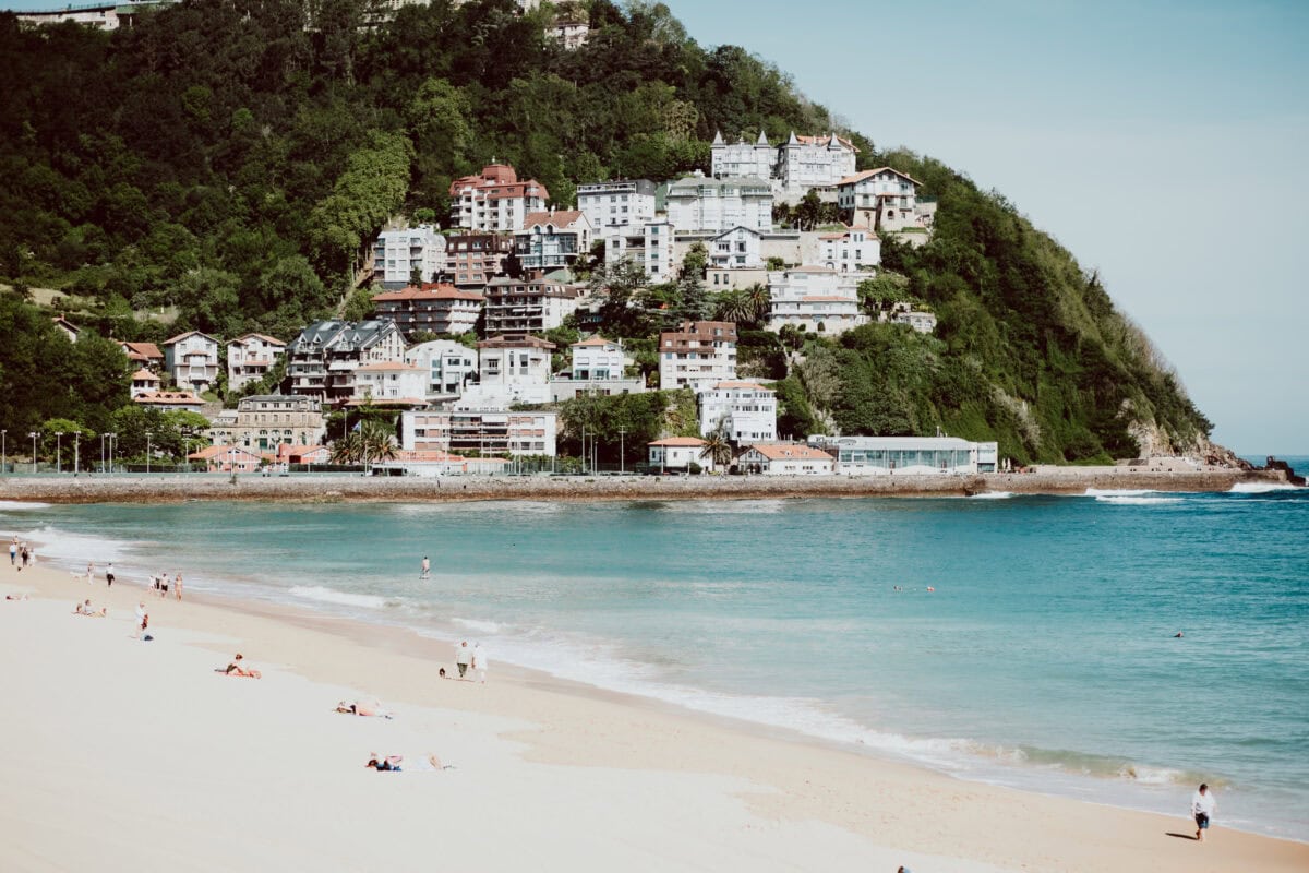 Beach with building and green hillside scenery.