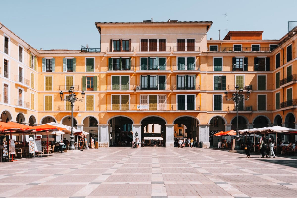 Empty square in front of a historic building with arcades.