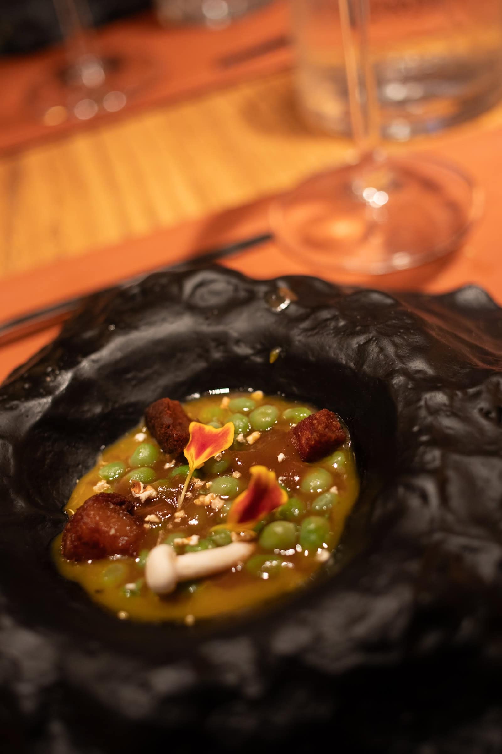 Gourmetteller mit Erbsen, Pilzen und Blüten dekoriert.