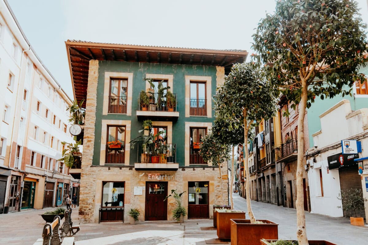 Grünes Gebäude an belebter Straße mit Bäumen.