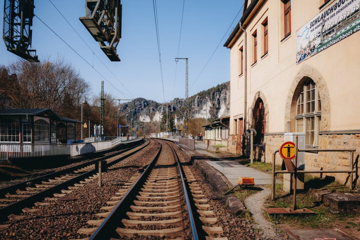 Bahngleise an kleinem Bahnhof vor Felslandschaft