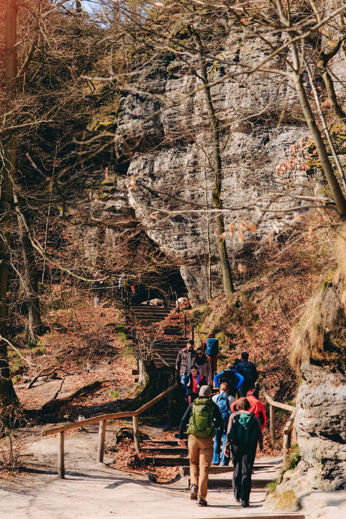 Wanderer steigen Treppe entlang Felswand im Wald