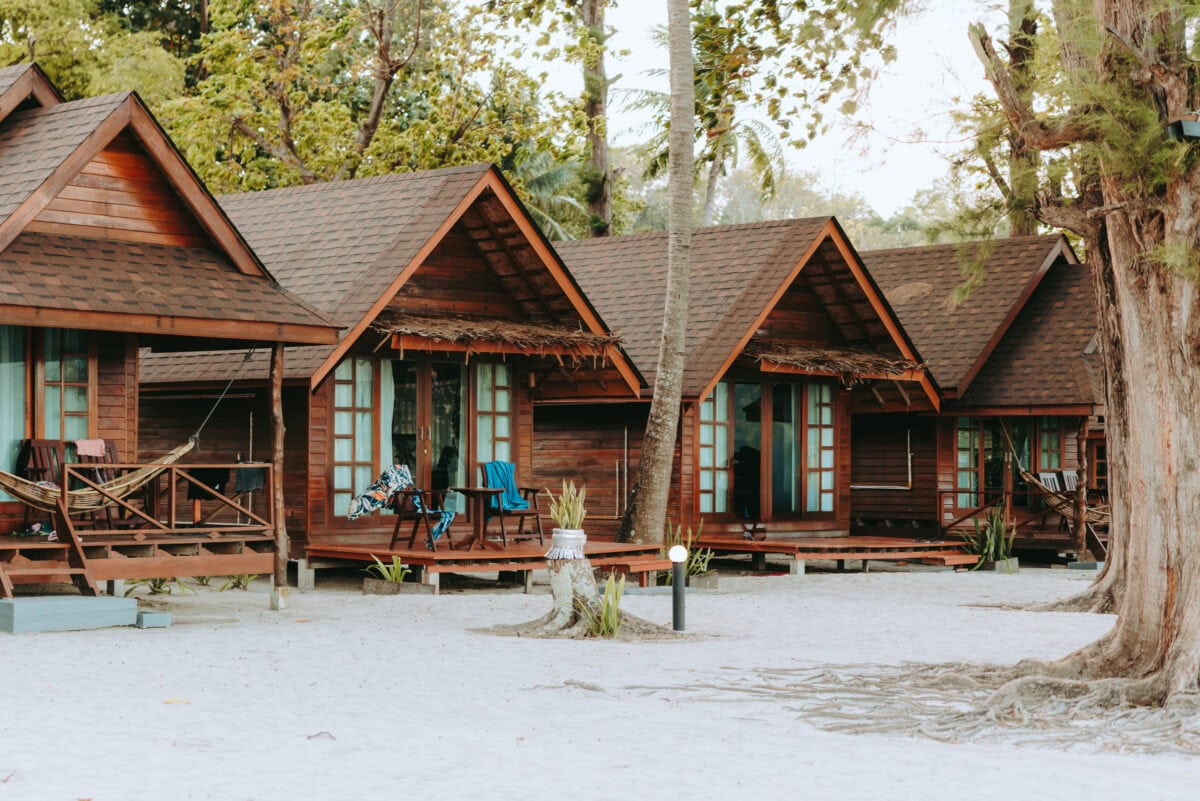 Wooden bungalows on the sandy beach under palm trees