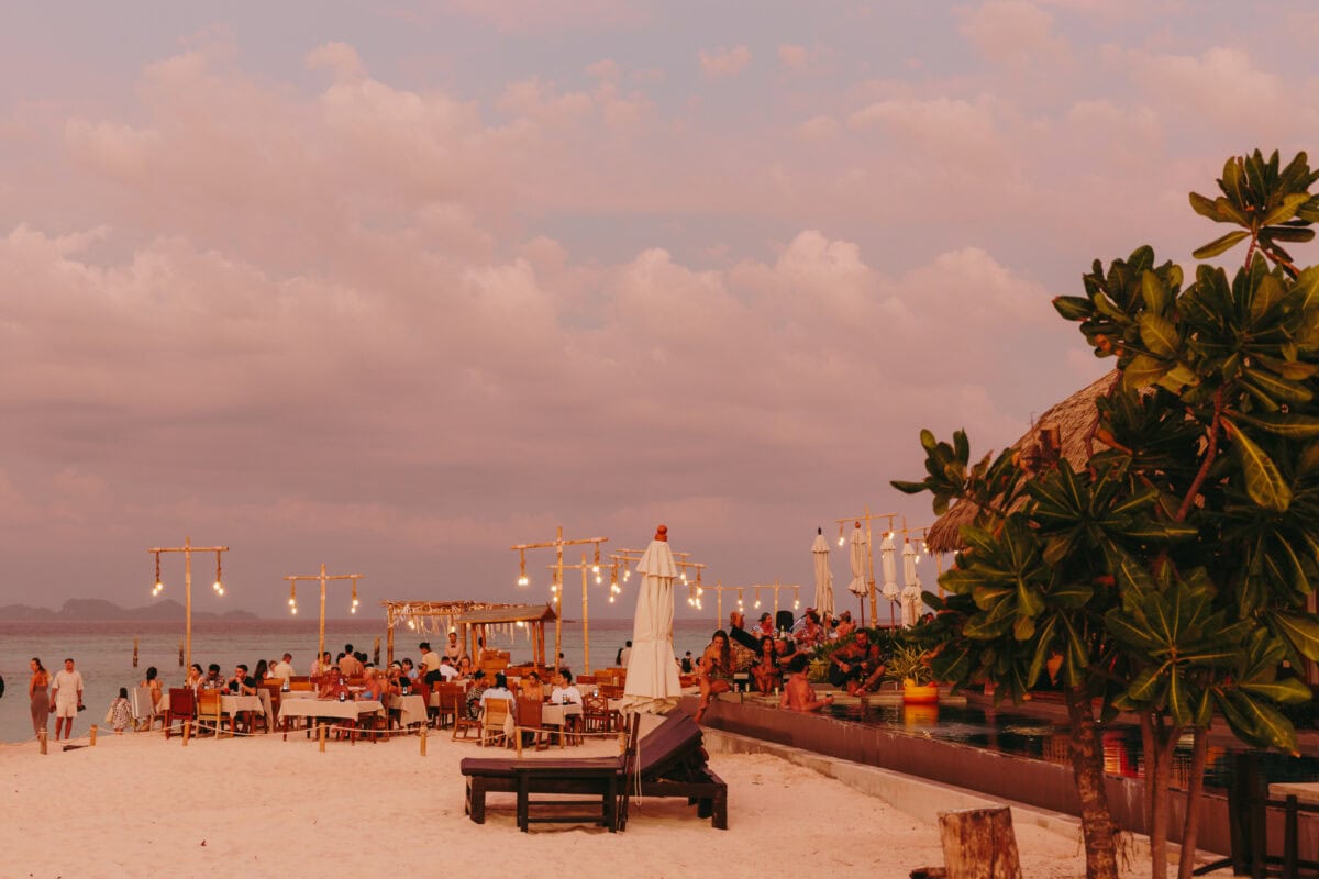 Beach restaurant at sunset with fairy lights and guests