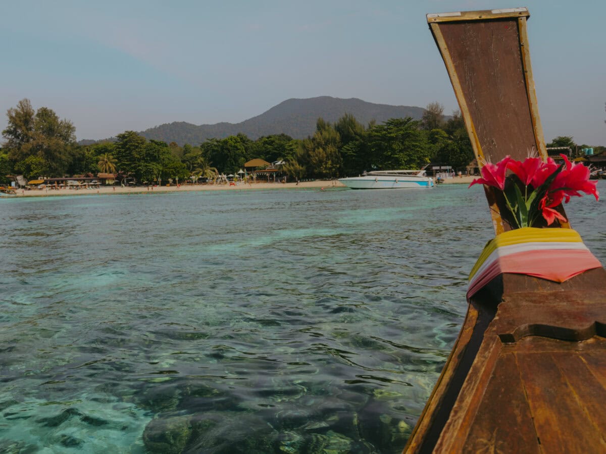 Longtail boat in front of a tropical beach with turquoise water