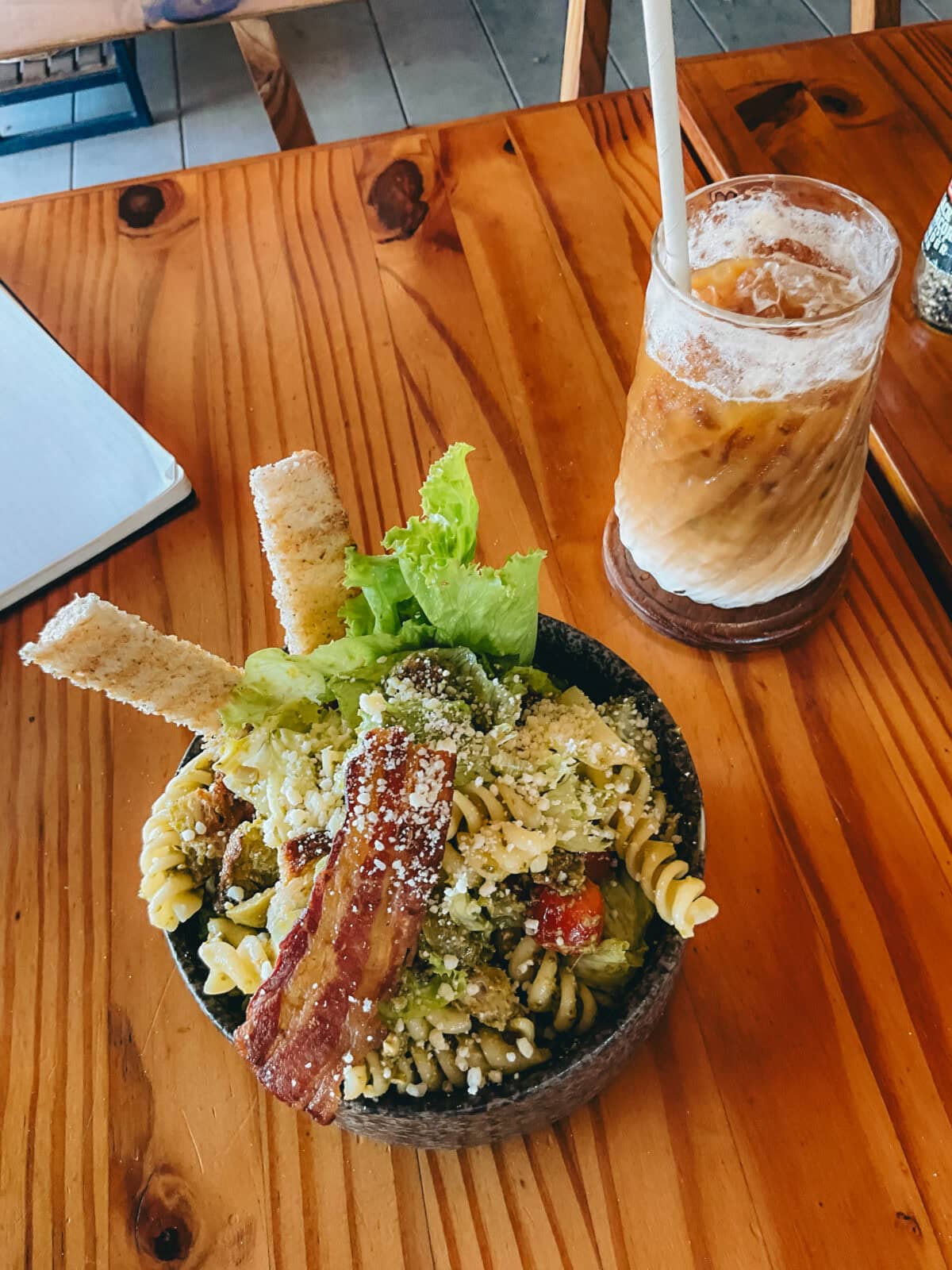 Pasta salad with bacon and iced coffee on a wooden table
