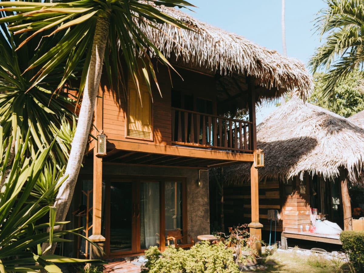 Tropical wooden house with thatched roof and palm trees