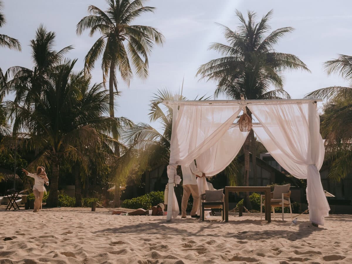 Beach pavilion with white curtains under palm trees